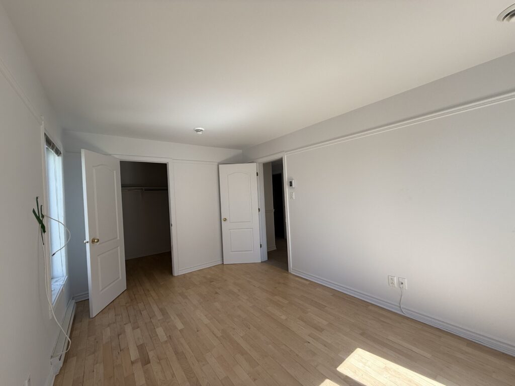 Chambre lumineuse avec plancher de bois et penderie ouverte dans un appartement du TriEau à McMasterville.