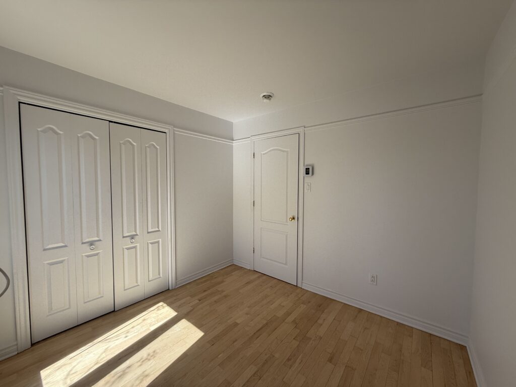 Chambre avec plancher de bois et placard à portes doubles dans un appartement du TriEau à McMasterville.