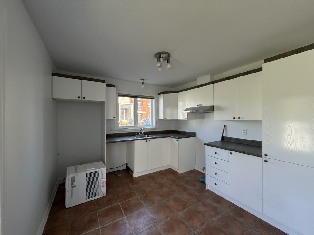 Cuisine d’un appartement du TriEau à McMasterville, avec armoires blanches et évier sous la fenêtre.