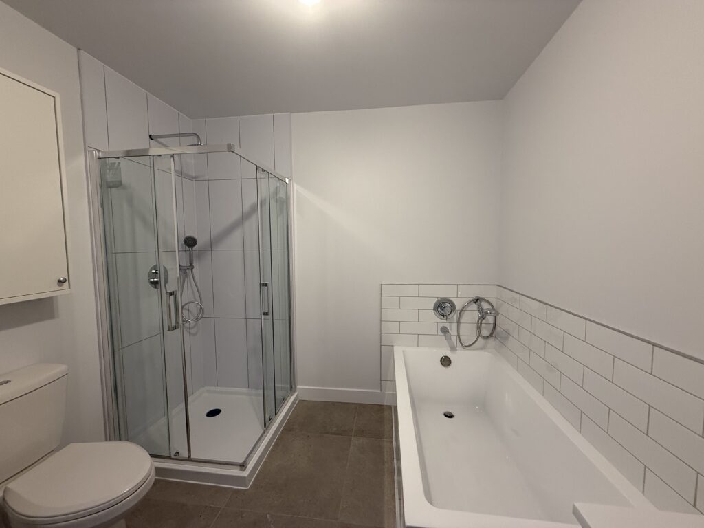 Salle de bain d’un appartement du TriEau à McMasterville, avec douche vitrée et baignoire séparée.