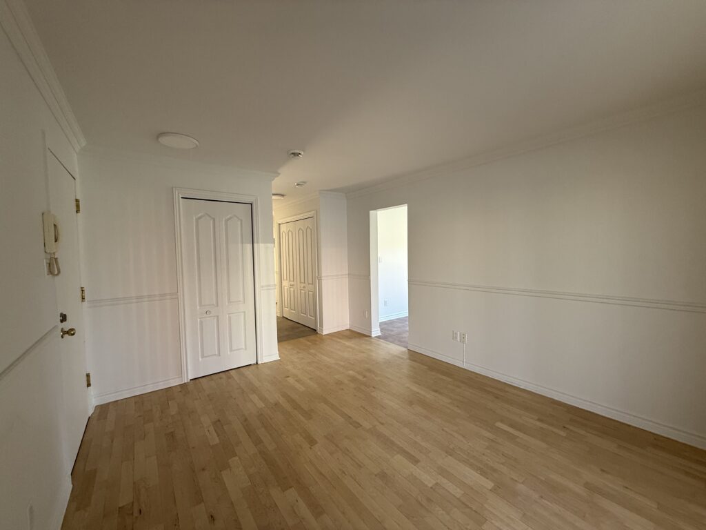 Salon avec plancher de bois et accès aux pièces adjacentes dans un appartement du TriEau à McMasterville.