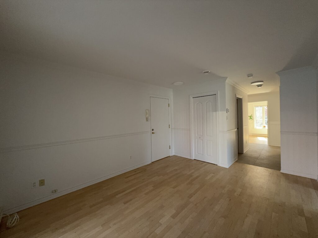 Séjour avec plancher de bois et vue vers l’entrée et le couloir d’un appartement du TriEau à McMasterville.
